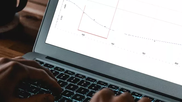 We see a laptop in close-up. The screen shows the user interface of an analysis and planning tool.