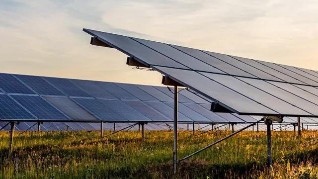 Open-field photovoltaic system on grass with sunset