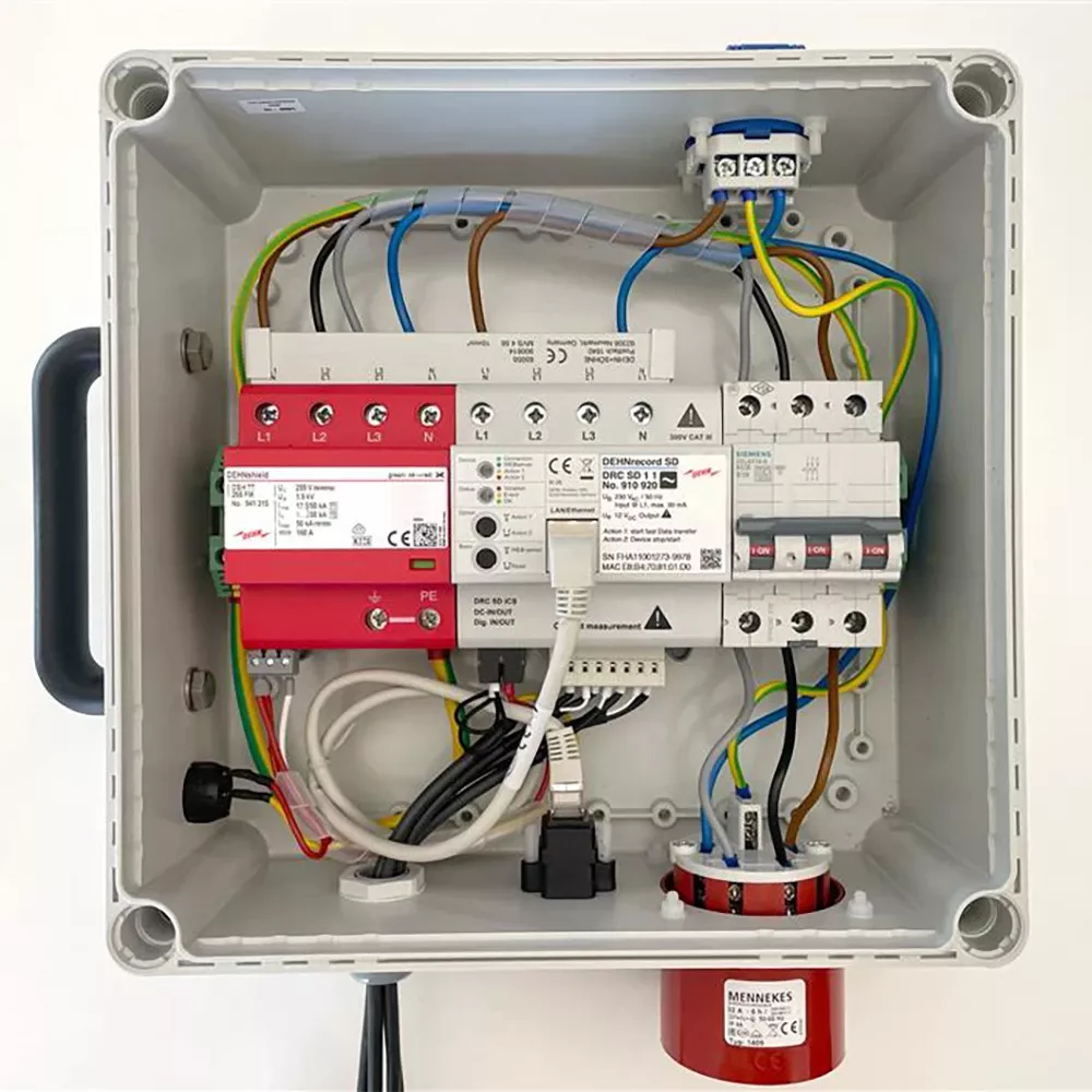 A captivating image displays a detailed electrical panel, where wires of vibrant red, blue, yellow, and green create a symphony of color. The neatly arranged connections and safety measures, including a red switch and a fire extinguisher, exude precision and organization, centering on the panels efficiency.