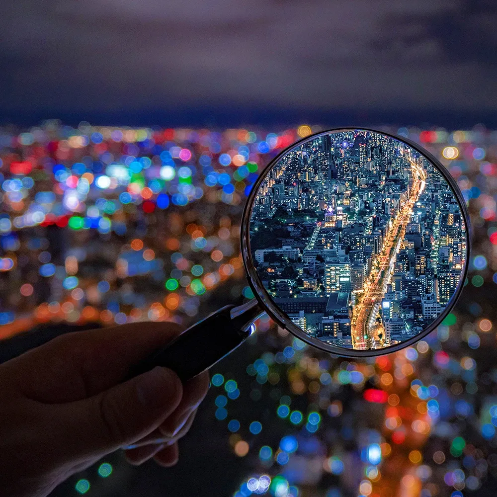 Magnifying glass highlighting a city street at night, symbolizing investigation, transparency, and complaint review processes.